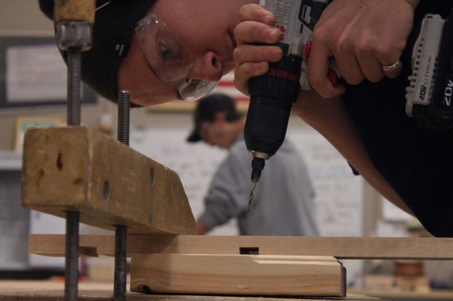 Jacob Cummins '23 uses the hand drill to cut holes in his wood to prep to put all his pieces together.
